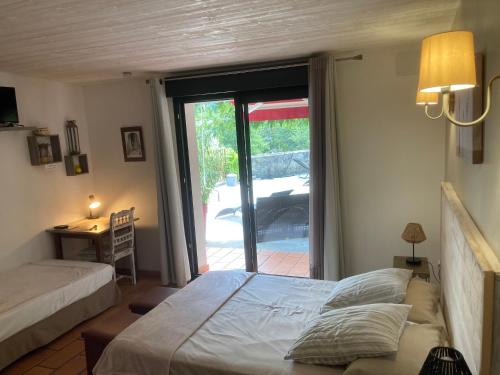 a bedroom with a bed and a sliding glass door at Logis des Magnans - Deux Chambres familiales pour 4 ou 5 personnes - in Sauve