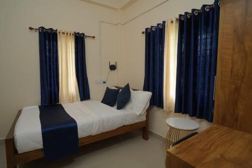 a bedroom with a bed with blue curtains and a table at Swasthika Homes in Pīrmed