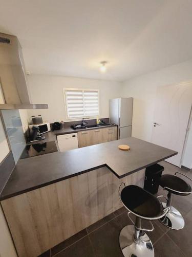 une cuisine avec un comptoir et deux tabourets de bar dans l'établissement La Belle des bois, à Pontenx-les-Forges