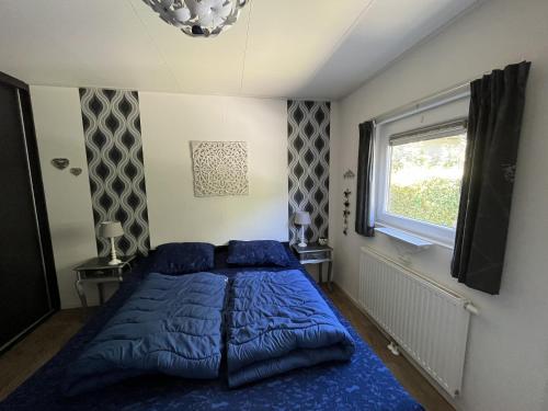 a bedroom with a blue bed and a window at Zandput 490 - Camping de Zandput in Vrouwenpolder