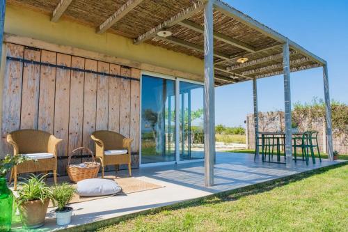 a covered porch of a house with chairs and a table at NEW Exclusive Lodges, Marzamemi, Noto in Pachino