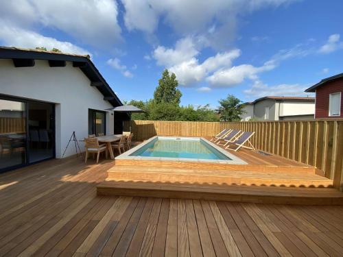 une terrasse avec une piscine, une table et des chaises dans l'établissement LUTZY Maison moderne au calme piscine, à La Teste-de-Buch