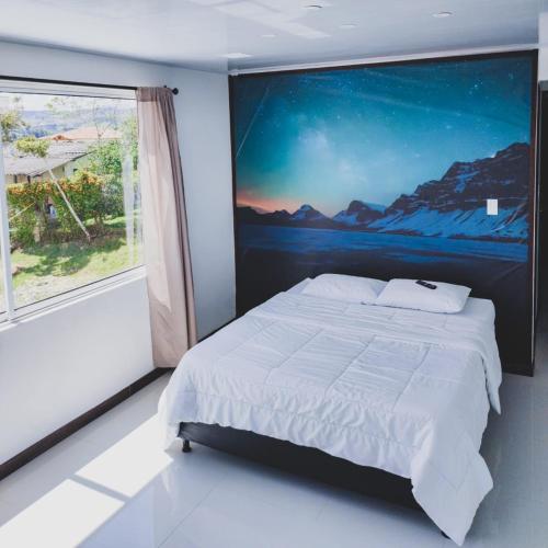 een slaapkamer met een bed met een schilderij aan de muur bij Hotel Ocaso Marinilla in Marinilla