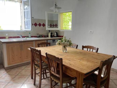 - une table en bois dans une cuisine avec un vase de fleurs dans l'établissement Jolie maison de ville, à Apt