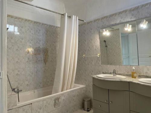une salle de bain avec une baignoire, un lavabo et un miroir dans l'établissement Jolie maison de ville, à Apt