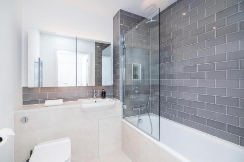 a bathroom with a tub and a toilet and a sink at Amazing 1BR wbalcony & view, Acton, Smarthost in London