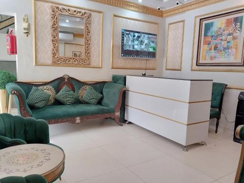 a living room with a green couch and a dresser at Golden One Hotel in Lahore
