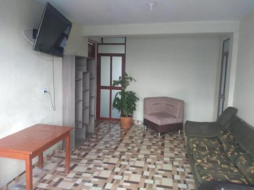 ein Wohnzimmer mit einem TV, einem Sofa und einem Tisch in der Unterkunft Inka Home - Ayacucho in Ayacucho