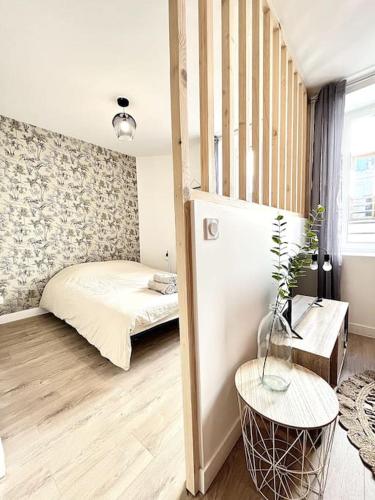 une petite chambre avec un lit et une table dans l'établissement La Tourmaline Rouge - Romans, à Romans-sur-Isère