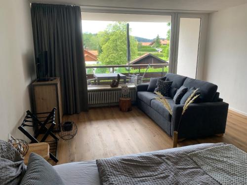 a living room with a couch and a large window at Staufen Herz NETFLIX WLAN in Oberstaufen
