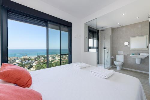 a bedroom with a large white bed and a bathroom at WintowinRentals New and Sea View in Torre de Benagalbón
