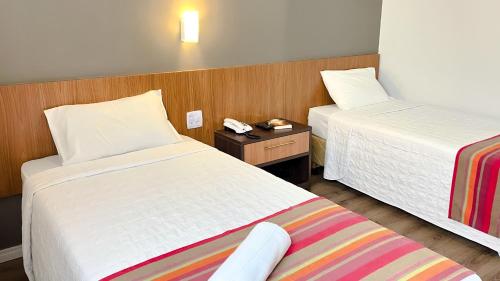 um quarto de hotel com duas camas e um telefone numa mesa em Itajaí Express Residence em Itajaí