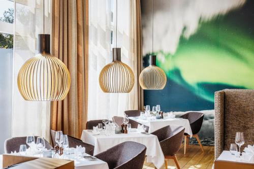 a restaurant with white tables and chairs and chandeliers at Akureyri - Berjaya Iceland Hotels in Akureyri