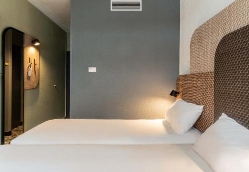 a bedroom with a bed with white sheets at B&B HOTEL Chartres Centre Cathédrale 3 étoiles in Chartres