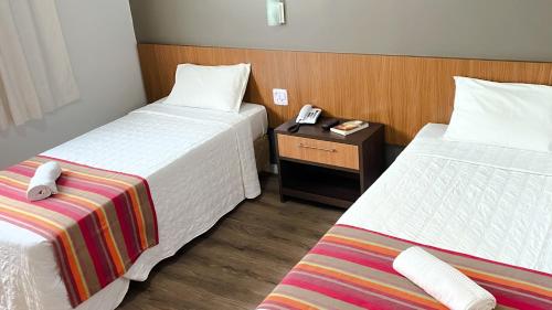 a hotel room with two beds and a phone on a table at Itajaí Express Residence in Itajaí