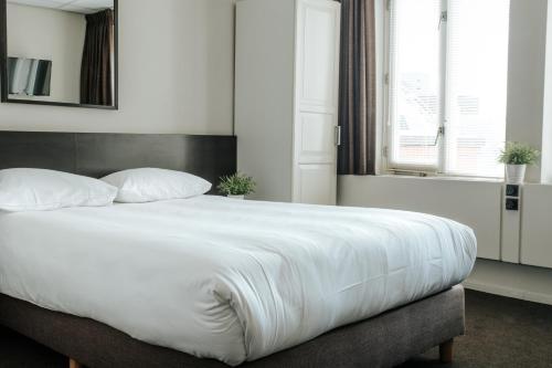 a bedroom with a large bed with white sheets at Queen Hotel in Eindhoven