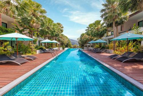 a pool at a resort with chairs and umbrellas at Club Wyndham Patong Hill, Phuket in Patong Beach
