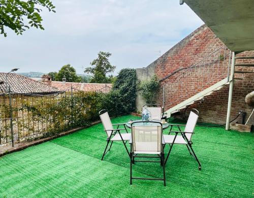 un patio con una mesa y sillas en un césped verde en Casa Vistabella, en Frassinello Olivola