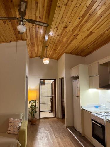 a kitchen with wooden ceilings and a living room at Kibala Hotel in Cıralı