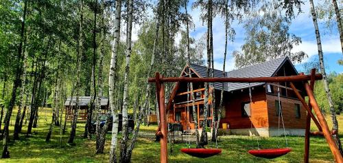 eine Blockhütte in einem Wald mit Schaukeln in der Unterkunft Cabana cu Mesteceni in Sighetu Marmaţiei