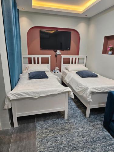 two beds in a room with a tv on the wall at afnan farm in Al Ḩamrānīyah