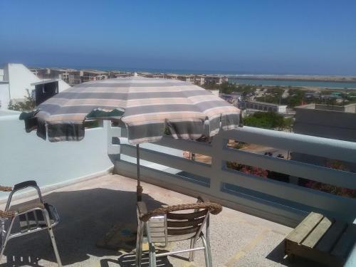eine Terrasse mit einem Sonnenschirm und Stühlen auf dem Dach in der Unterkunft Beach house in Kenitra