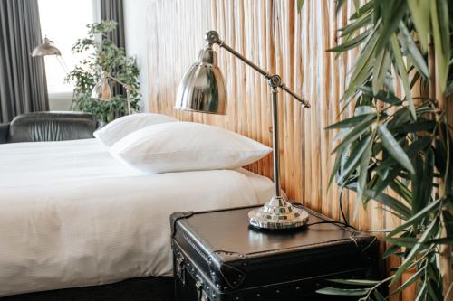 a hotel room with a bed and a lamp on a table at Queen Hotel in Eindhoven