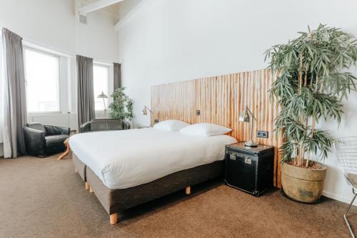 a bedroom with a large bed and two potted plants at Queen Hotel in Eindhoven