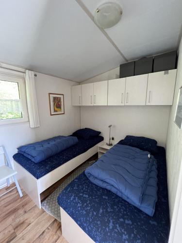 two beds in a small room with blue pillows at ZP 470 - Camping de Zandput in Vrouwenpolder