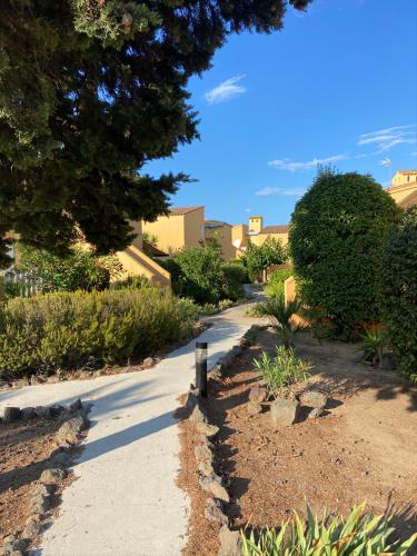 un trottoir dans un parc planté d'arbres et de buissons dans l'établissement Résidence les 4 soleils, au Cap d'Agde
