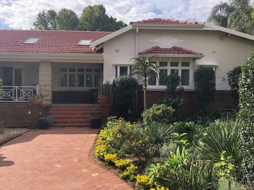 uma casa branca com um telhado vermelho e uma entrada de tijolos em Self-catering two-bedroom flat Scottsville PMB em Pietermaritzburg