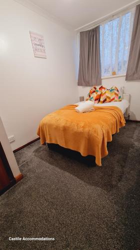 a bedroom with a bed with an orange blanket at Flourish House in Kent