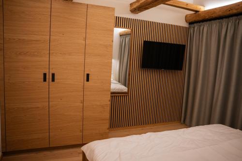 a bedroom with wooden cabinets and a bed and a television at Neu! Ferienhaus Moritz & Josie (zur Alleinnutzung) / Eröffnung 01. Juli 2023 in Ohlstadt