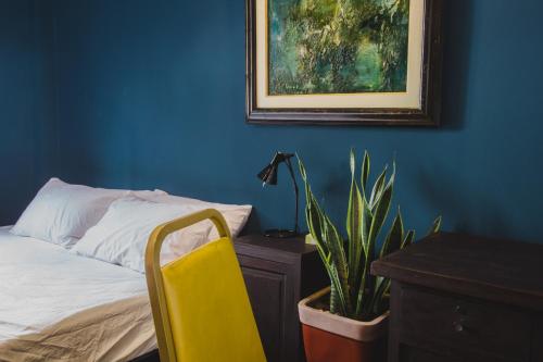 a bedroom with a bed and a yellow chair and a plant at CAMP Dakao a curated accomodation in Ho Chi Minh City