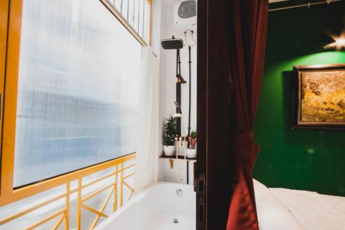 a bathroom with a white tub and a green wall at CAMP Dakao a curated accomodation in Ho Chi Minh City