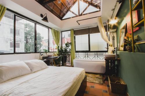 Schlafzimmer mit einem Bett, einer Badewanne und Fenstern in der Unterkunft CAMP Dakao a curated accomodation in Ho-Chi-Minh-Stadt