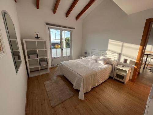 a white bedroom with a bed and a window at Bahía de Pedreña in Pedreña