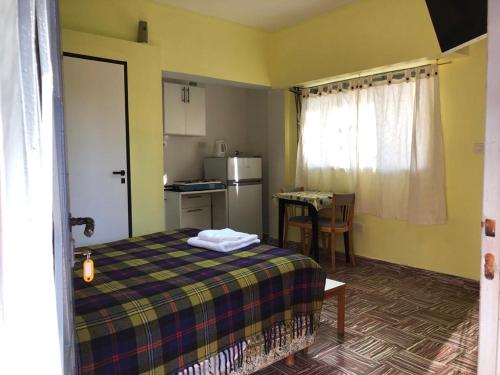 1 dormitorio con 1 cama y cocina con mesa en Monoambiente en km3 en Comodoro Rivadavia