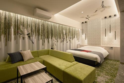 sala de estar con sofá verde y cama en ツルガナホテル-レジャーホテル-ラブホテル en Sendai