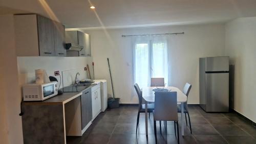 une cuisine avec une table et des chaises et un micro-ondes dans l'établissement Givors Centre Duplex meublé, à Givors