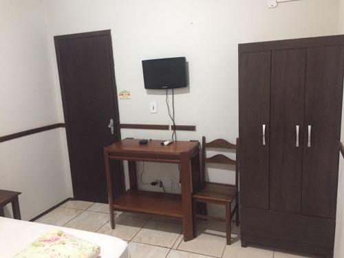 a bedroom with a desk and a tv and a cabinet at ORSI HOTEL in Araguari