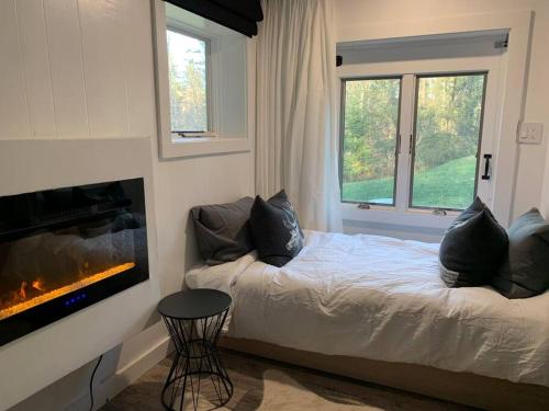 1 dormitorio con 1 cama junto a la chimenea en Beautiful renovated chalet mn to Stratton, en Strattonwald