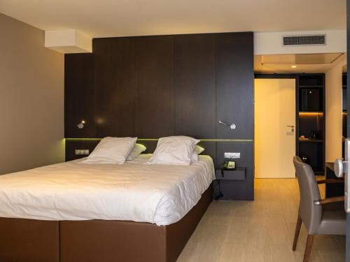 um quarto com uma cama grande e uma cadeira em Tower Hotel Aalst em Aalst