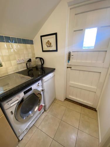 uma lavandaria com uma máquina de lavar roupa e uma janela em The Guesthouse hideaway em Hordle