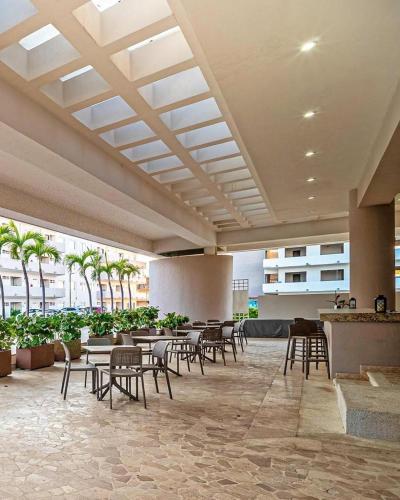 a lobby with tables and chairs and palm trees at Depa de lujo en Acapulco diamante con club de playa a pie-Precio especial in Acapulco