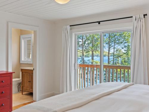 Un dormitorio con una cama y una ventana grande. en Getaway Cottage LAKE FRONT Muskoka Room Kayaks, en Dwight