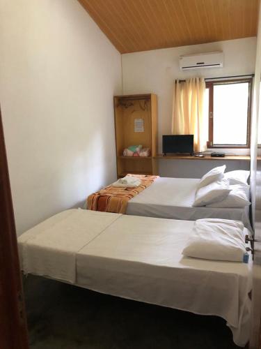 two beds in a small room with a window at Pousada Aba da Serra in São Joaquim do Monte