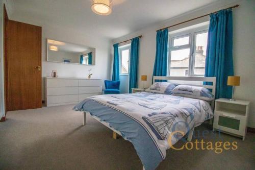1 dormitorio con 1 cama con cortinas azules y ventana en Quayside - Rye, en Rye