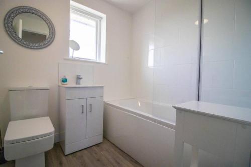 baño blanco con bañera, aseo y lavamanos en Rosemary Cottage Camber Sands - 1 min to beach en Camber