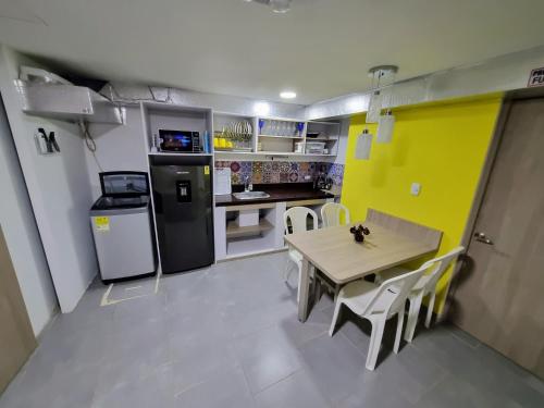 a small kitchen with a table and a yellow wall at Tranquilo Apartamento Central Cerca a la Playa Puerto Colombia in Puerto Colombia
